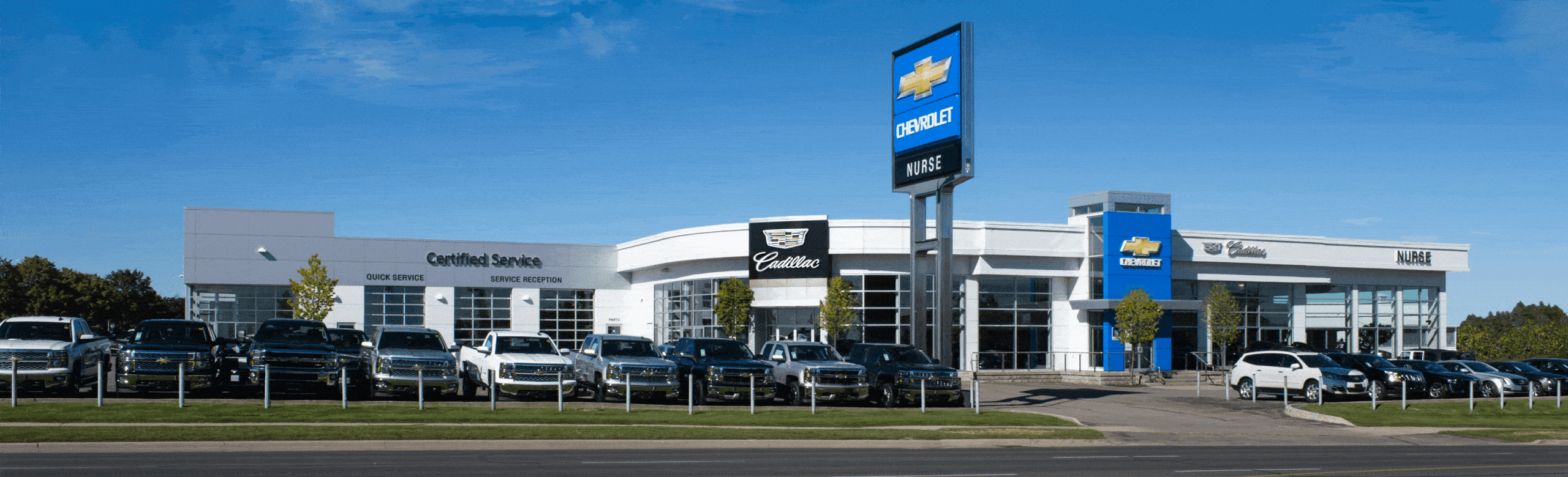 Chevrolet and Cadillac dealership exterior with parked cars, featuring certified service center.