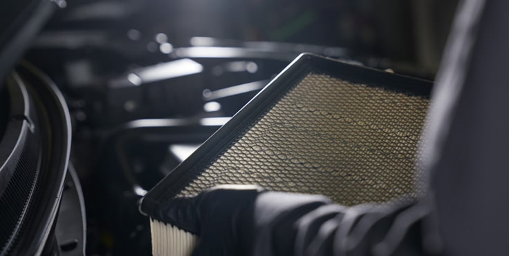 Mechanic handling car air filter during engine maintenance, emphasizing automotive care and air filter replacement.