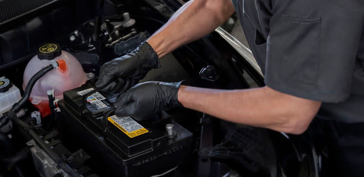 Mechanic handling car air filter during engine maintenance, emphasizing automotive care and air filter replacement.