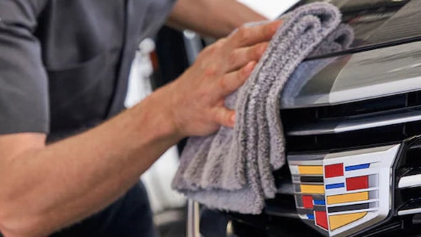 Mechanic wearing gloves checks car engine oil with dipstick in vehicle maintenance.