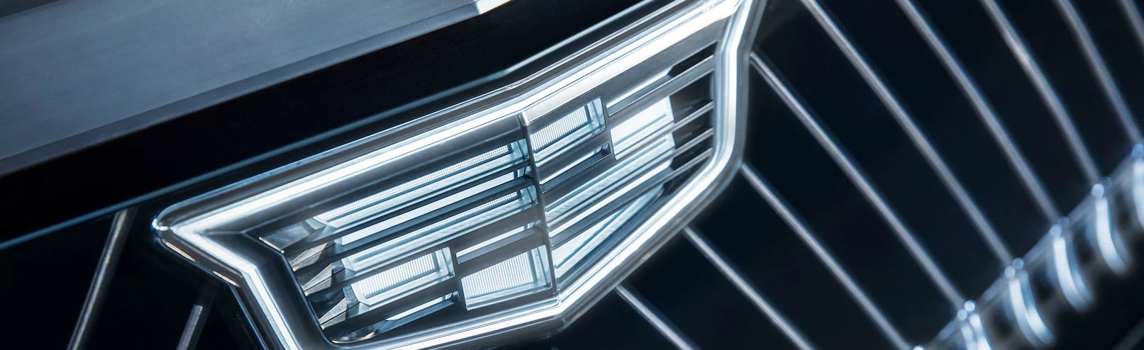 Close-up of a sleek Cadillac logo on a modern black grille, highlighting luxury automotive design.