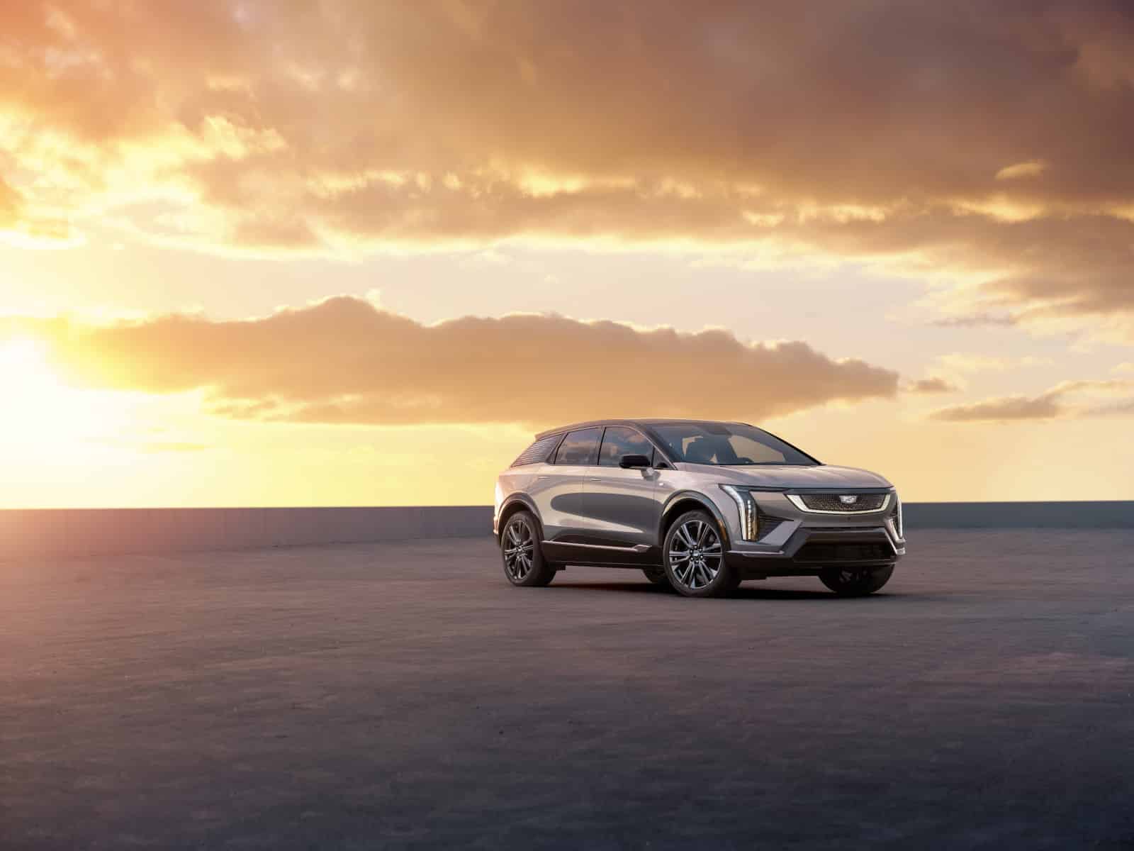 Silver SUV parked on open pavement under a dramatic sunset sky, highlighting its modern design.