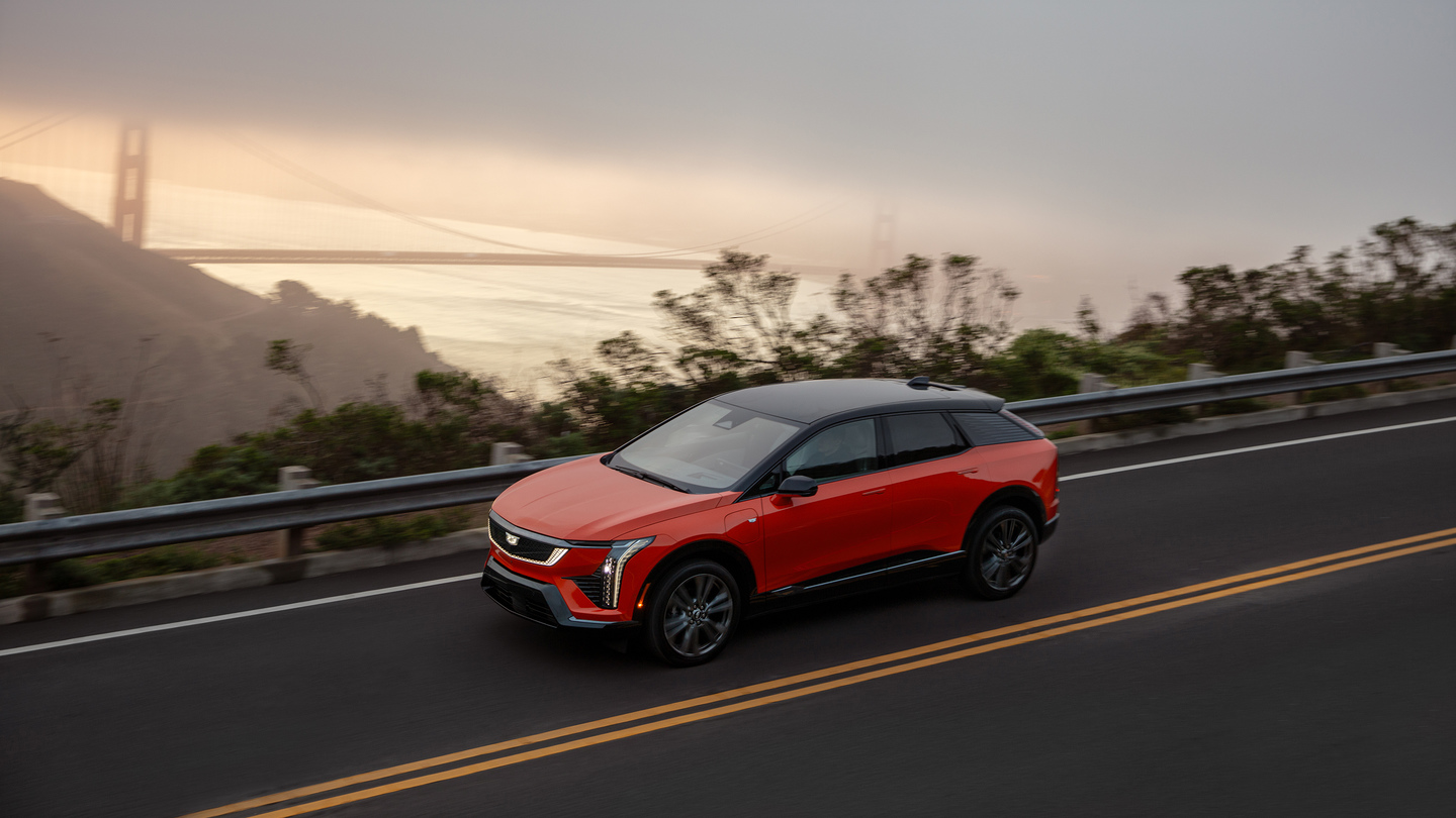 Red SUV driving on a coastal road with the Golden Gate Bridge in the background.