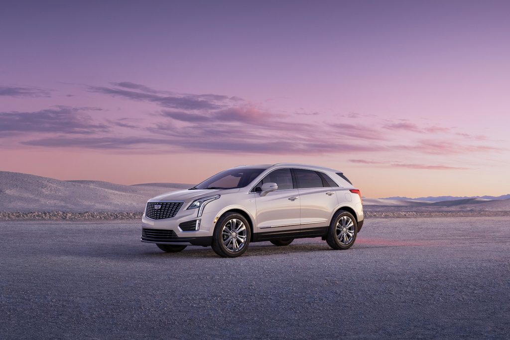 White SUV parked on a desolate landscape at sunset, featuring a pastel sky with soft clouds.